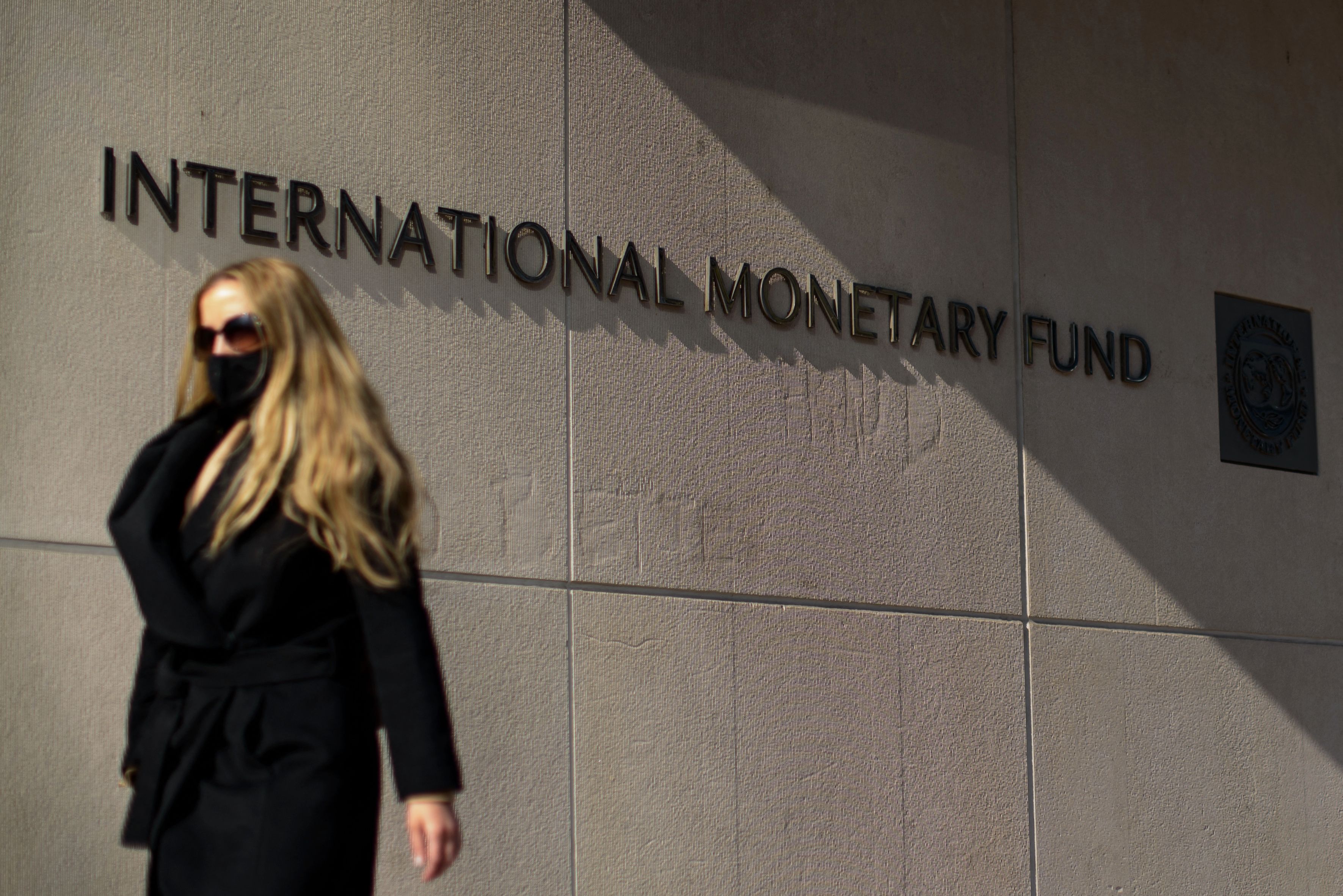 WASHINGTON: File photo shows, a woman walks past an International Monetary Fund headquarters (IMF) building in Washington, DC. The IMF will withhold funds to Afghanistan amid the uncertainty over the status of the leadership in Kabul. - AFPn