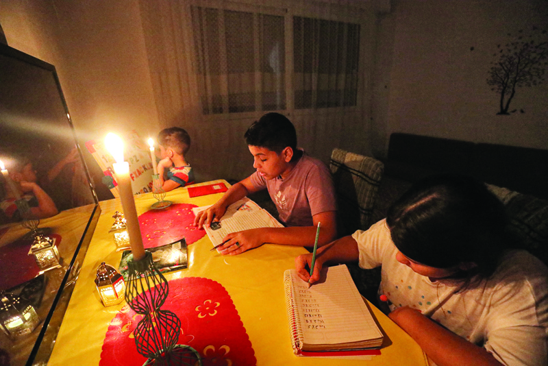 TRIPOLI: Children study by the light of candlesticks at night in a flat in Libya's capital Tripoli. - AFPn