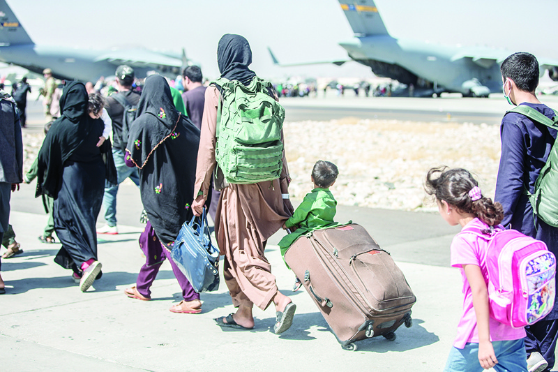 KABUL: In this handout image courtesy of the US Marine Corps, a child (center) looks at the aircraft as he is strolled towards his flight during an evacuation at Hamid Karzai International Airport, Kabul yesterday.-AFPn