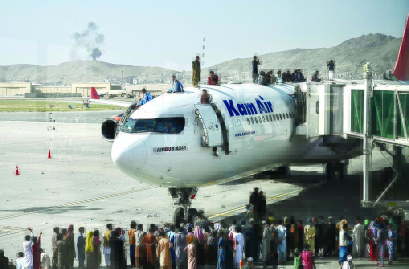 KABUL: People climb atop a plane as they try to flee at Kabul airport yesterday. - AFP photos