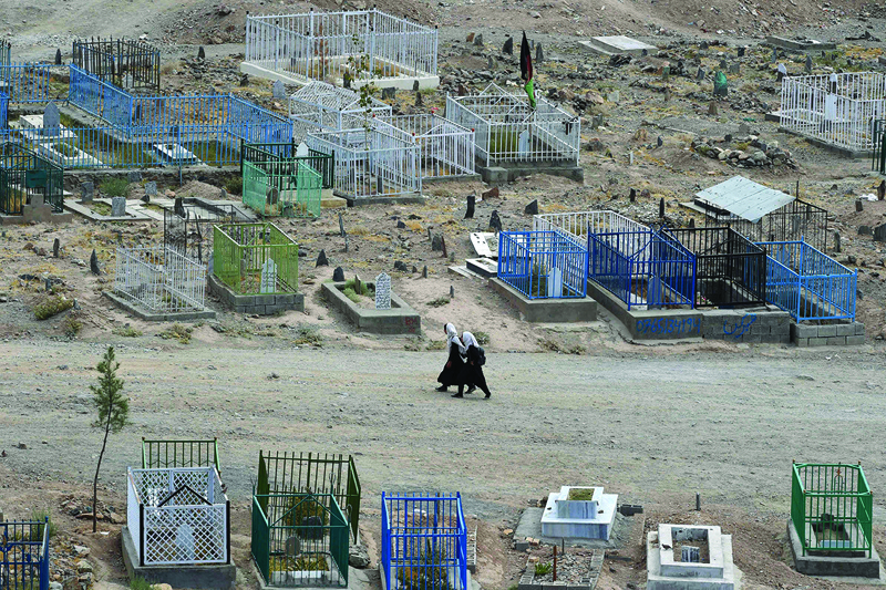 KABUL: Afghan schoolgirls walk through a pathway along the Qasaba cemetery yesterday. - AFP n