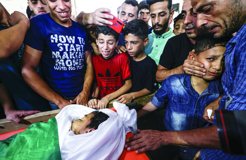 GAZA CITY: Friends and relatives of Palestinian Omar Hassan Abu Al-Nile, 12, who died of wounds he sustained during a Zionist attack last week, mourn during his funeral in Gaza City yesterday.-AFPn