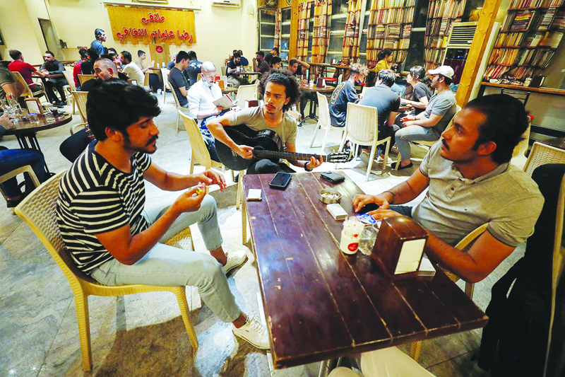 BAGHDAD: Mohammed, 23, plays the guitar as he sits with his friends at a coffee shop in the Karrada district of the capital on Aug 6, 2021. - AFP n
