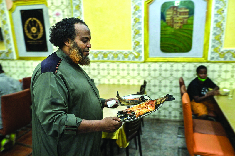 Omar Hamdani, proprietor of one of the city's oldest restaurants, Chez Hamdani, serves up Yemeni fish to lunchtime customers at his restaurant in Djibouti on April 11, 2021. – AFP photosn