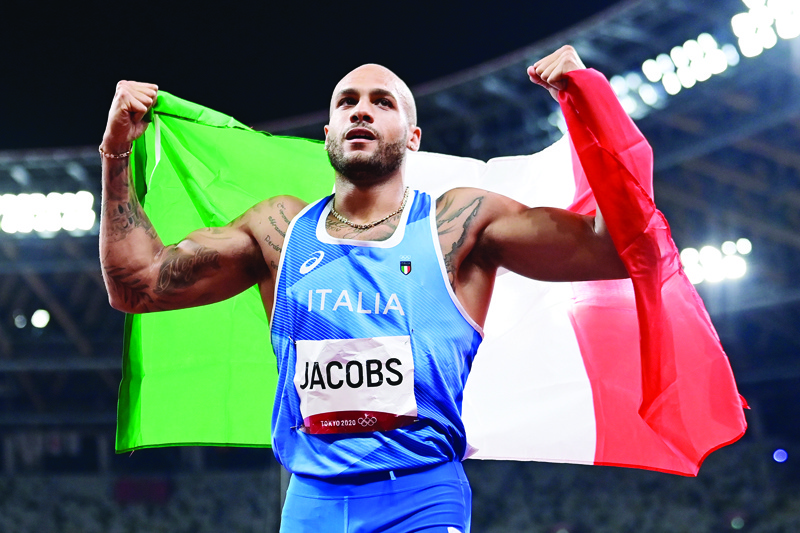 TOKYO: Italy's Lamont Marcell Jacobs celebrates with the flag of Italy after winning the men's 100m final during the Tokyo 2020 Olympic Games at the Olympic Stadium in Tokyo yesterday. - AFPn