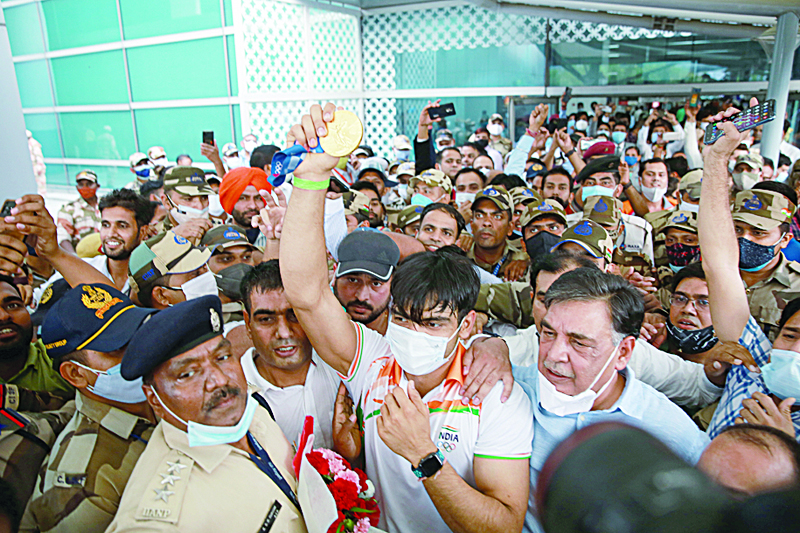 NEW DELHI: Gold medalist India's Neeraj Chopra, surrounded by his fans and security personnel displays his medal upon his arrival at the airport in New Delhi yesterday, after competing in the men's javelin throw event in the Tokyo 2020 Olympics. - AFPnn