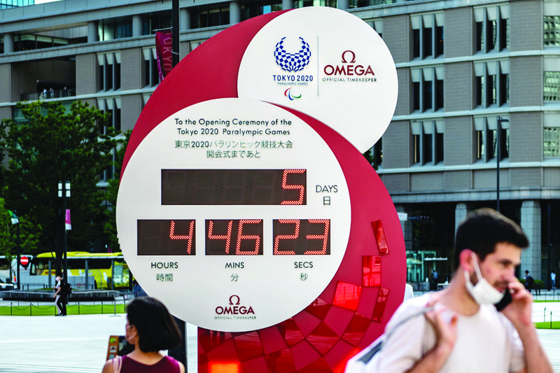 TOKYO: People walk in front of a countdown clock for the Tokyo 2020 Paralympic Games five days before the opening ceremony, outside Tokyo station in Tokyo yesterday. - AFPn