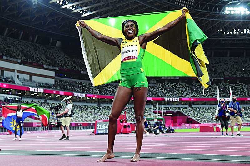 TOKYO: Jamaica's Elaine Thompson-Herah celebrates with the flag of Jamaica after winning the women's 200m final during the Tokyo 2020 Olympic Games at the Olympic Stadium in Tokyo yesterday. - AFPn