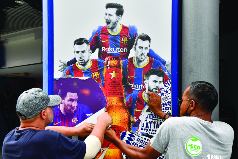 BARCELONA: Workers remove posters featuring Barcelona's departing Argentinian forward Lionel Messi at the Camp Nou stadium in Barcelona yesterday. - AFPn