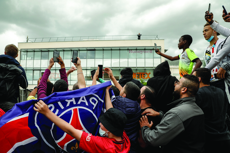 LE BOURGET: Supporters try to spot an aircraft that just landed as they gather outside Le Bourget airport, north of Paris, as Argentinian football player Lionel Messi was expected to arrive yesterday. - AFPn