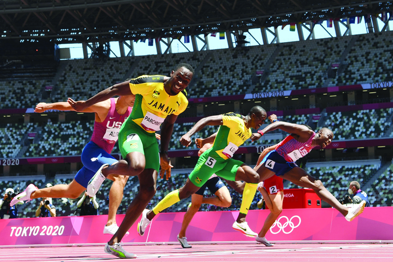 TOKYO: Jamaica's Hansle Parchment (left) crosses the finish line to win ahead of second-placed USA's Grant Holloway (right) and third-placed Jamaica's Ronald Levy (center) in the men's 110m hurdles final during the Tokyo 2020 Olympic Games at the Olympic stadium in Tokyo yesterday. - AFPn