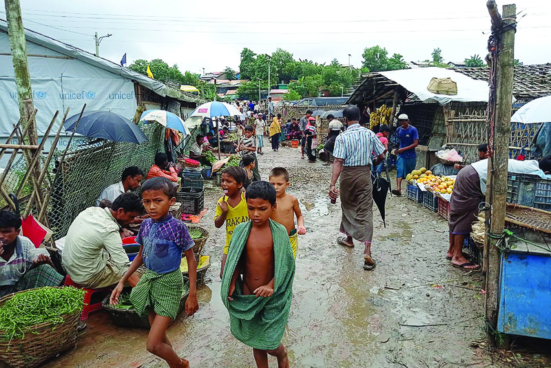 UKHIA, Bangladesh: Rohingya refugees walk along a path at Kutupalong refugee camp in Ukhia yesterday. - AFPn