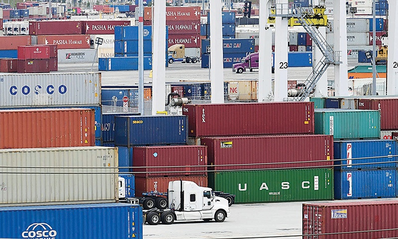 SAN PEDRO, US: In this file photo, container trucks make their way past stacked containers at the Port of Los Angeles in San Pedro, California. —AFP