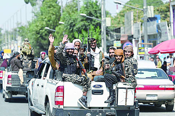 KABUL:  Taleban fighters wave as they patrol in a convoy along a street in Kabul yesterday. —AFP