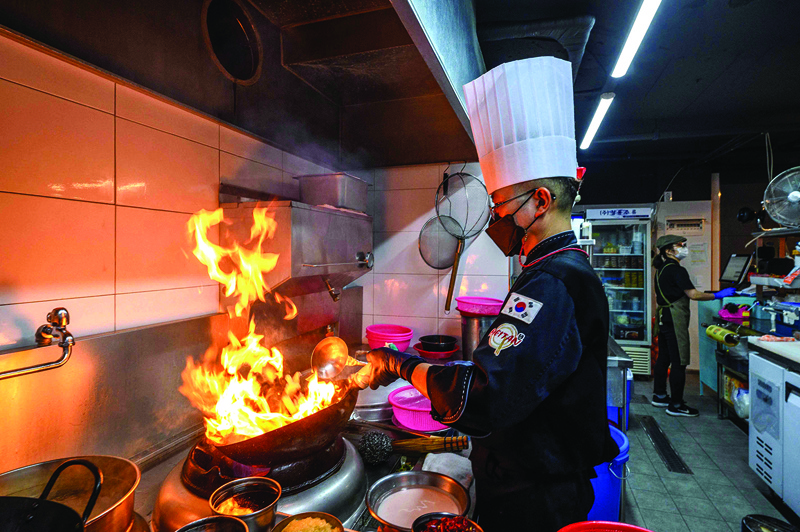 This picture shows Chinese food kitchen owner and chef Park Chan-chul cooking a meal before it is delivered to a customer, at the 5Km Kitchen, a business set up in March this year to rent out kitchen spaces for food companies that only do deliveries in Seoul.—AFPn