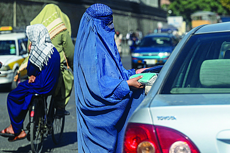 KABUL: An Afghan burqa clad woman sells face masks to the commuters at a traffic intersection in Kabul yesterday. – AFP n