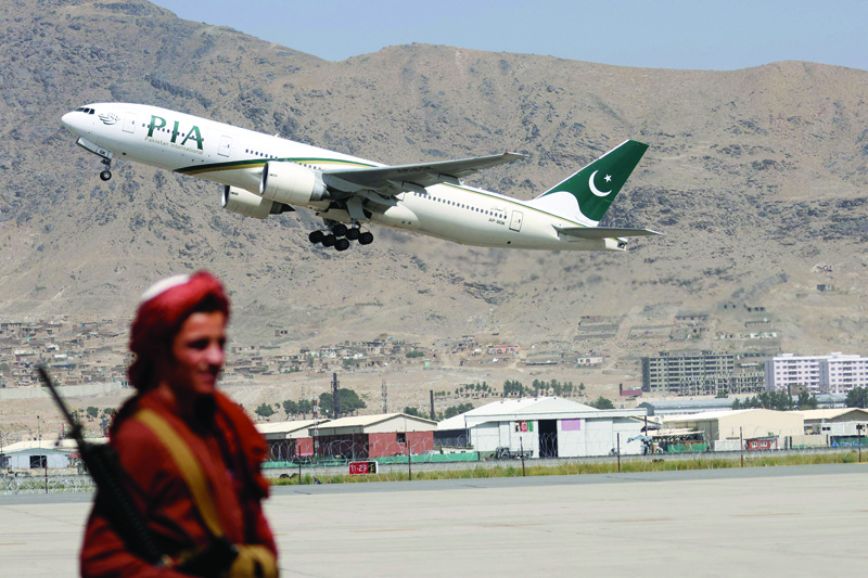 KABUL: A Taleban fighter stands guard as a Pakistan International Airlines plane, the first commercial international flight to land since the Taleban retook power last month, takes off with passengers onboard at the airport yesterday. - AFP n
