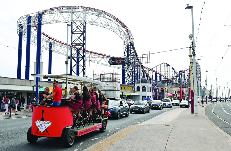 BLACKPOOL, UK: A group of women, celebrating a hen party, travel on a 'pedal pub' past the Pleasure Beach in Blackpool, north west England.-AFPn
