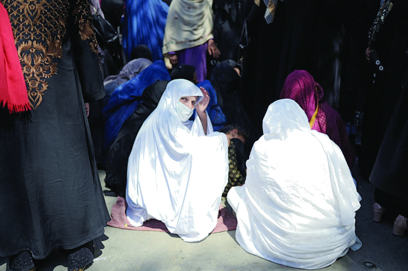 KABUL: Women wait in front of a bank to withdraw money in Kabul yesterday.-AFPn