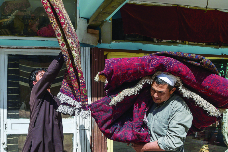 KABUL, Afghanistan: Workers carry carpets on their shoulders at Chicken Street in Kabul yesterday.-AFPnn