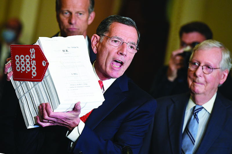 WASHINGTON, US: US Senator John Barrasso, Republican of Wyoming, with Senators Mitch McConnell (right), and John Thune (left, rear),holds a copy of the reconciliation bill as he speaks after the Republican policy luncheon at the US Capitol in Washington, DC Tuesday.-AFPnnn