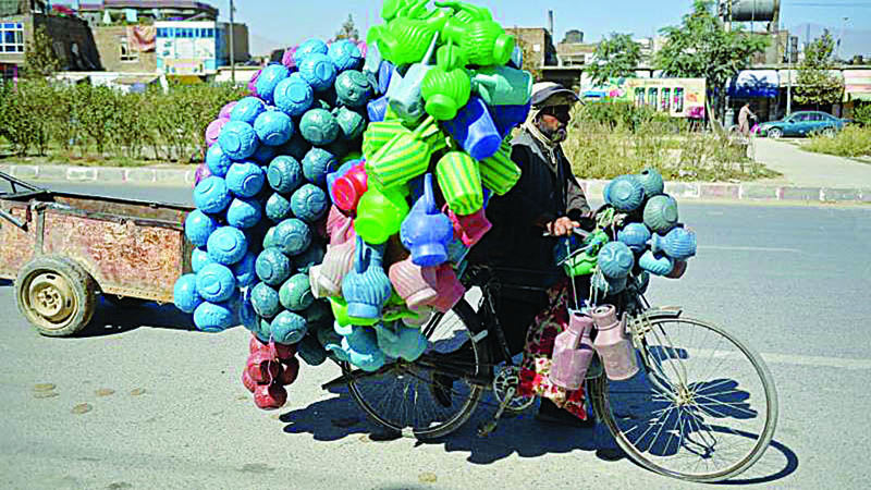 KABUL: A man pushes his bicycle loaded with plastic cans along a roadside in Kabul Sunday.-AFPnn