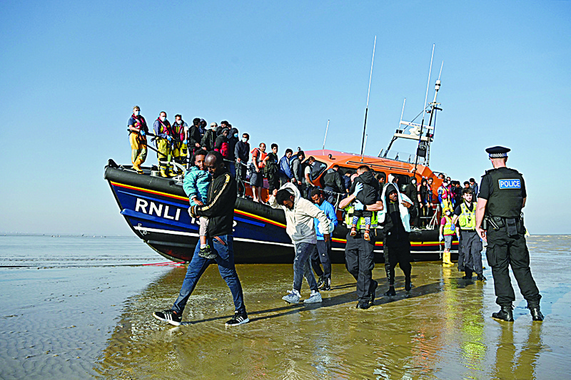 KENT: Migrants carry children as they are escorted to be processed after being picked up by an RNLI (Royal National Lifeboat Institution) lifeboat while crossing the English channel at a beach in Dungeness, southeast England. - AFPn
