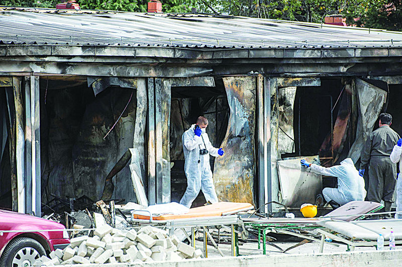 TETOVO: Forensic scientists and firefighters work at the site of a fire at a COVID-19 clinic in Tetovo yesterday. - AFP n