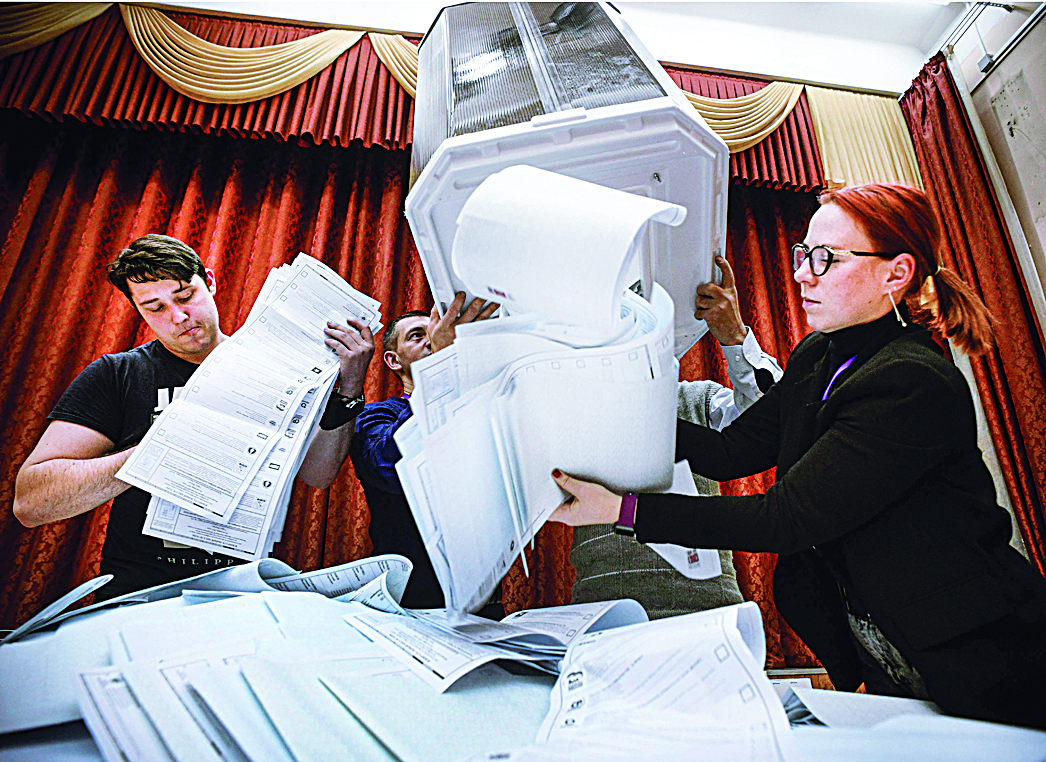 MOSCOW: Members of a local electoral commission empty a ballot box at a polling station after the last day of the three-day parliamentary election in Moscow. - AFP n