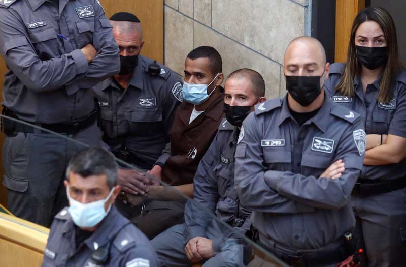 NAZARETH: Palestinian Munadel Infeiat, one of the six prisoners who had tunneled out of the high security Gilboa prison, is surrounded by Zionist police officers as he appears at the magistrates' court yesterday following his recapture. - AFP n