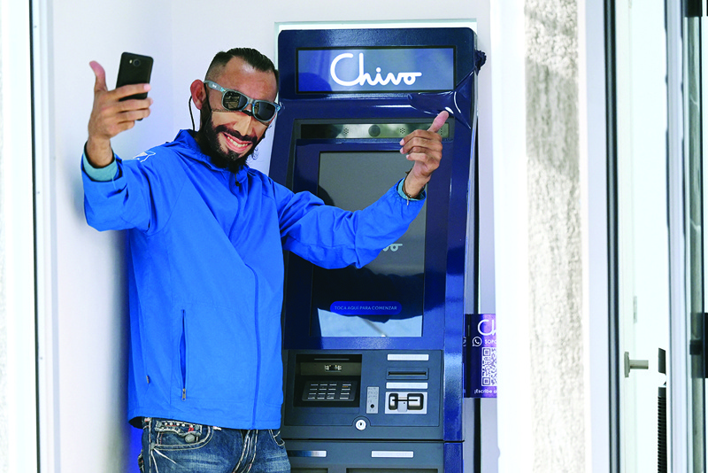 SAN SALVADOR: A man wearing a protective facemask with the image of Salvadoran President Nayib Bukele poses for a picture at a bitcoin ATM yesterday. - AFP n