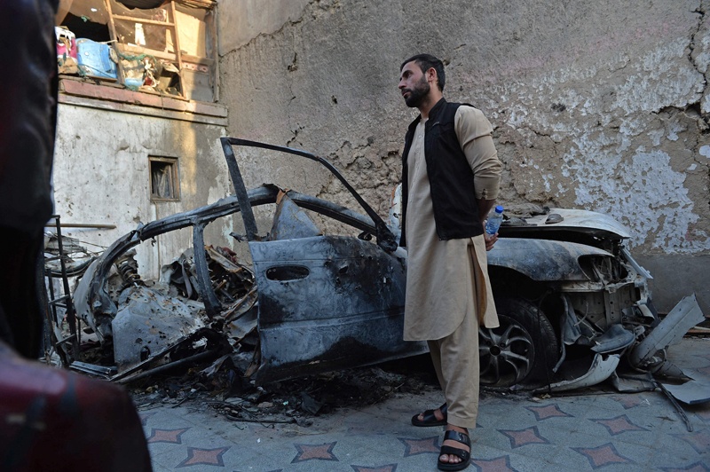 KABUL: Aimal, brother of Ezmarai Ahmadi, stands next to the wreckage of a vehicle that was damaged in a US drone strike in the Kwaja Burga neighborhood yesterday. – AFP n