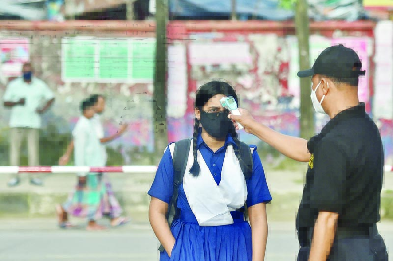 DHAKA: A guard checks the temperature of a student upon her arrival at Rajuk Uttara Model College yesterday. – AFP n