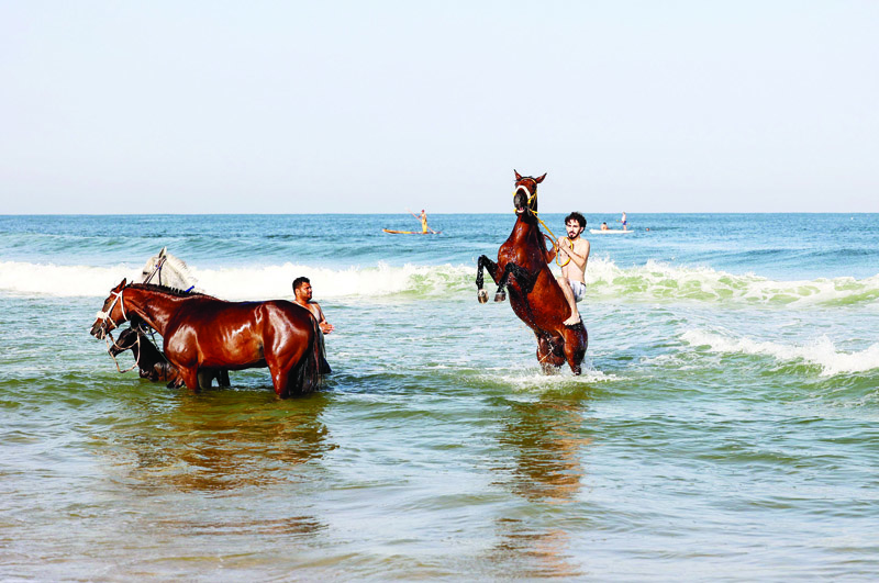 GAZA: Palestinian men ride horses at the beach in Gaza City yesterday. - AFP n