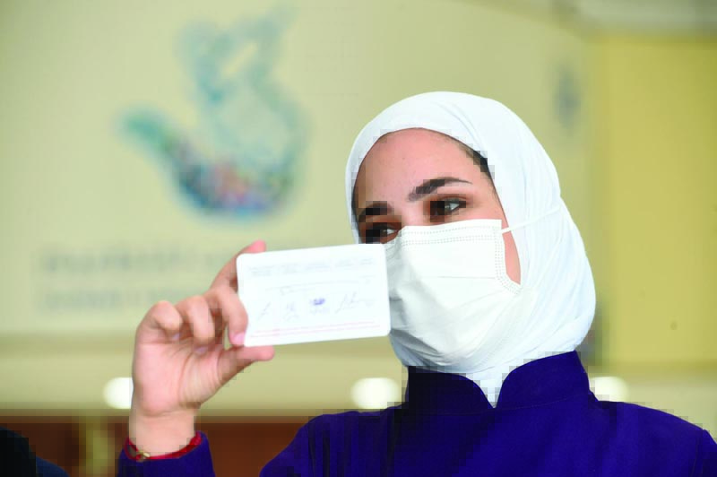 KUWAIT: An employee of Kuwait's Ministry of Health shows a vaccination card issued to vaccinated people at the Kuwait Vaccination Center in Mishref yesterday. - Xinhuan
