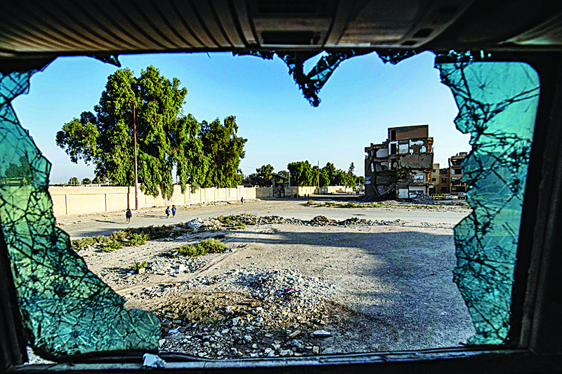 RAQA: Syrian students walking to school are seen through a shattered glass in the northern city of Raqqa. - AFP n