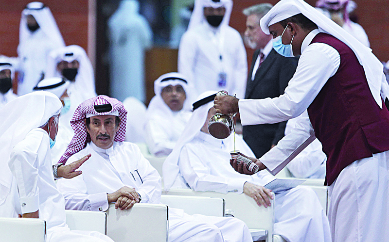 AL WAKRAH, Qatar: A waiter pours a drink as Qataris sit during a campaign rally for Qatar's inaugural Shura Council election, in Al-Wakrah.- AFP n