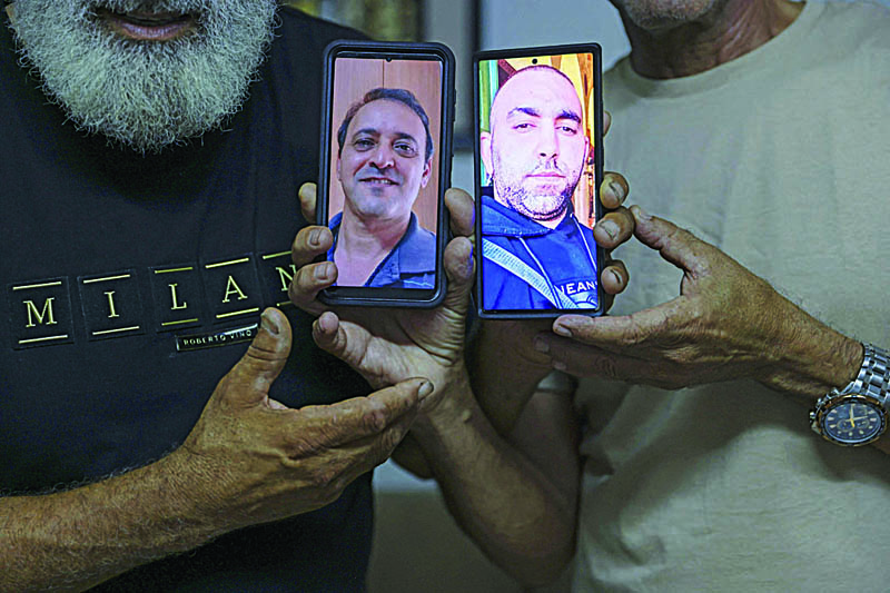 LOD: Malek Hassuna (left) carries a picture of his late son Mussa (center-right), who was shot dead by Jewish vigilantes on May 10, poses for a picture with Effi Yehoshua (right) as he carries a picture of his late brother Yigal.- AFP n