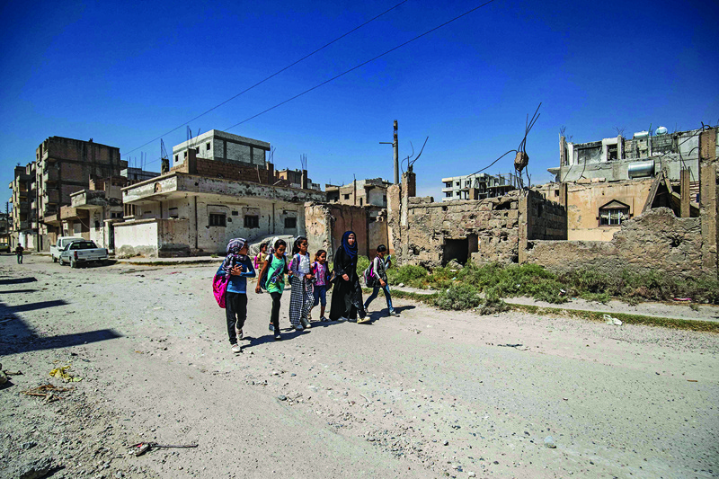 RAQA: Syrian students walk to school past damaged buildings in the northern city of Raqqa. - AFP n