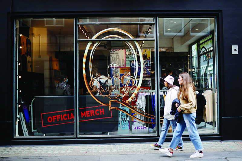 Pedestrians walk past the windows of a new store selling official merchandise of legendary British rock group Queen in central London.—AFP photosn