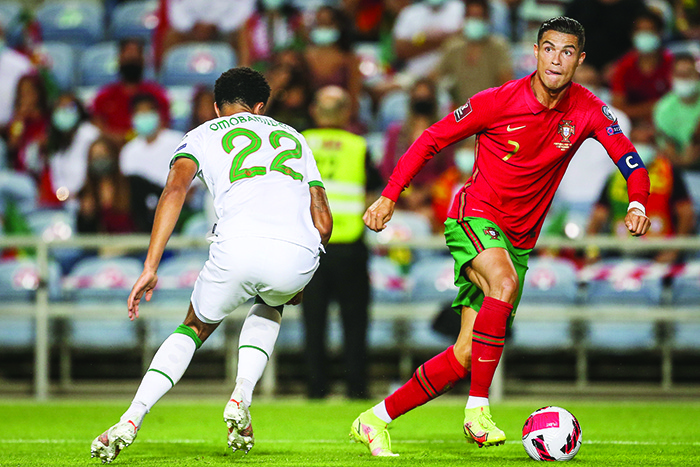 LOULE: Portugal’s forward Cristiano Ronaldo (right) fights for the ball with Ireland’s defender Andrew Omobamidele during the FIFA World Cup Qatar 2022 European qualifying round group A football match between Portugal and Ireland at the Algarve stadium in Loule, near Faro, southern Portugal, on Wednesday. —AFP