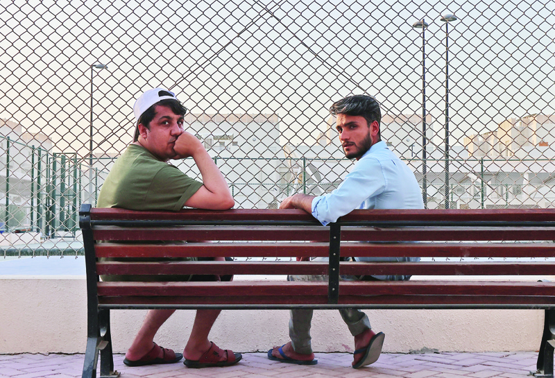 DOHA: Afghan refugees Khalid Andish (right), 24, and Ahmad Wali Sarhadi, 28, sit on a bench near their accommodation at Park View Villas, a Qatar's 2022 FIFA World Cup residence designated to host the event's guests and participants, transformed into a housing center for Afghan refugees, in Doha, on Thursday. - AFPn