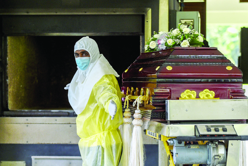 COLOMBO: A cemetery worker wearing Personal Protective Equipment (PPE) prepares to place the coffin of Eliyantha White, a local shaman who claimed he had super natural powers to end the pandemic and died of the COVID-19 coronavirus, inside the furnace at the crematorium of the Colombo General Cemetery yesterday. - AFP nn