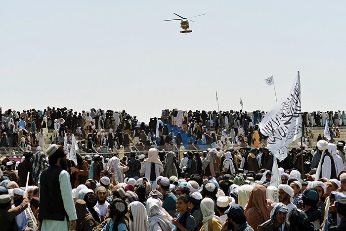KANDAHAR: A helicopter flies above supporters gathered yesterday to celebrate the US withdrawal of all its troops out of Afghanistan. — AFP