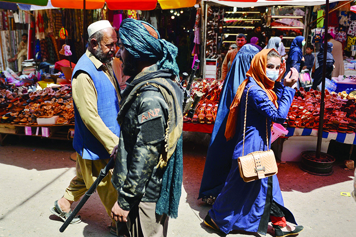 KABUL: A Taleban fighter (C) walks past shoppers along Mandawi market in Kabul yesterday a day after the US pulled all its troops out of the country to end a brutal 20-year war — one that started and ended with the hardline Islamist in power. — AFP