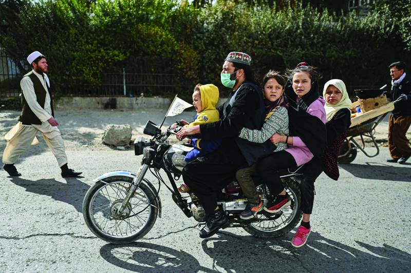 KABUL: A man rides a motorcycle with a boy and three girls along a street in Kabul city. - AFP n