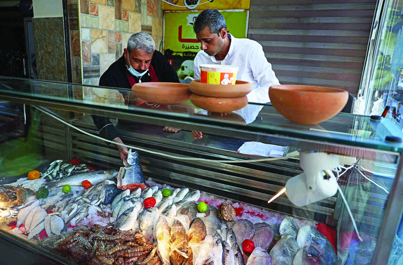 Moin (left) and Mustapha Abu Hassira display Fresh fish at Roma fish restaurant owned by the Abu Hassira family in Gaza City.-AFP photos n