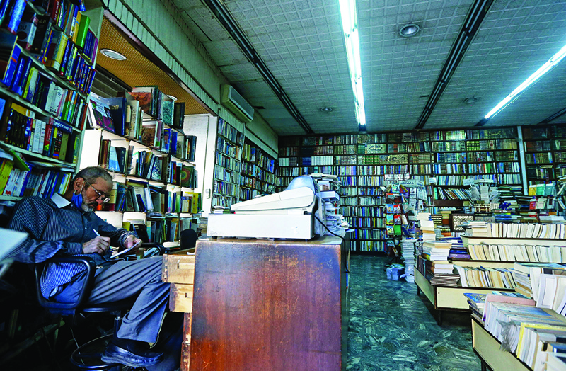 An employee checks a book at the Al-Nouri bookstore, which was founded in 1930 and is threatened with closure, in the Syrian capital Damascus on October 17, 2021. - The Damascus bookshops and publishing houses that once stood as beacons of Syria's intellectual life are being replaced with shoe shops and money changers, as culture falls casualty to crisis. (Photo by LOUAI BESHARA / AFP)