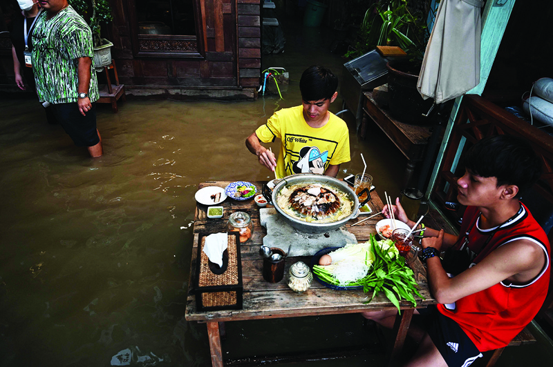 In this photo taken on Oct 7, 2021, shows people enjoying dinner at the Chaopraya Antique Cafe, as floodwater from the Chao Phraya River surges into the restaurant in Nonthaburi province north of Bangkok. – AFP nn