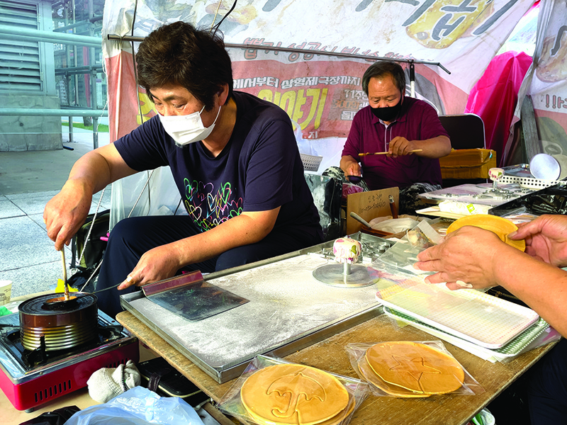 Street vendors Jung Jung-soon (left) and her husband Lim Chang-joo (right) make dalgonas, a crisp sugar candy featured in the Netflix smash hit series Squid Game, for which they were hired to be on set to make during production. –AFP photosn